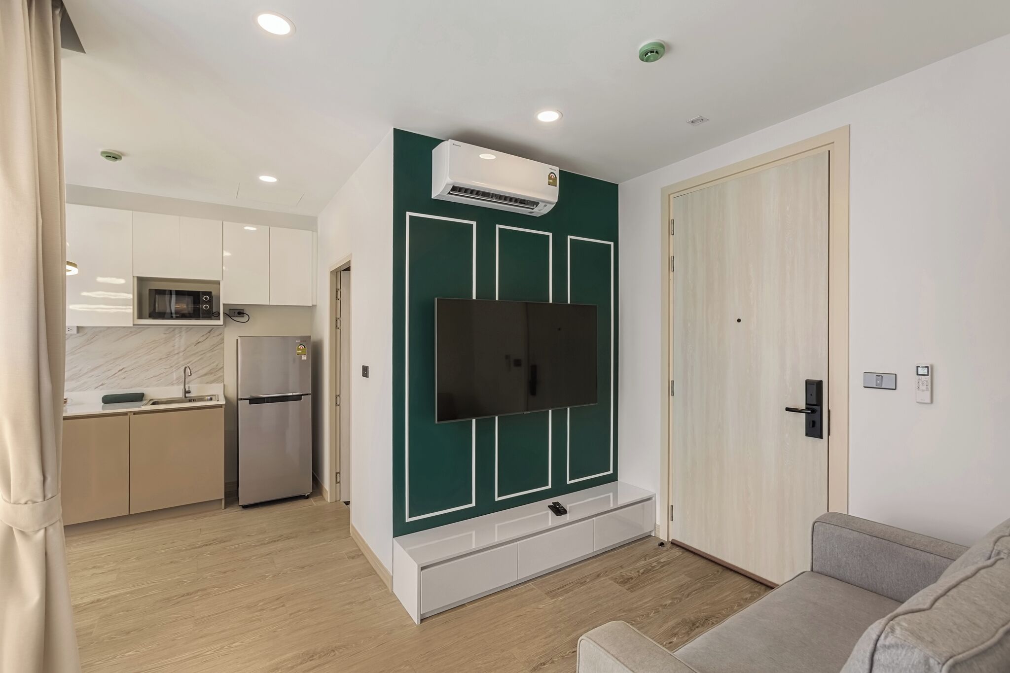 Un apartamento moderno con cocina, sala de estar con televisor de pantalla plana y puerta con interruptor de luz.