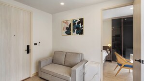 Un soggiorno moderno con divano, poltrona e letto. Due opere d'arte incorniciate decorano la parete.