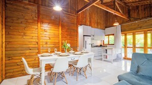 A modern kitchen with white cabinets and a dining area with a white table set for four. - Wooden Retreat Near Lagoa da Conceicao Knu0170 (Florianópolis)
