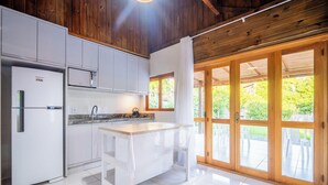 A modern kitchen with white cabinets, a stainless steel refrigerator, and a wooden ceiling. - Wooden Retreat Near Lagoa da Conceicao Knu0170 (Florianópolis)