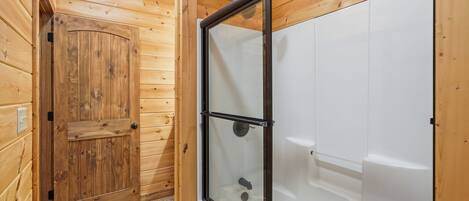 A wooden cabin with a glass-enclosed shower area and a wooden door.