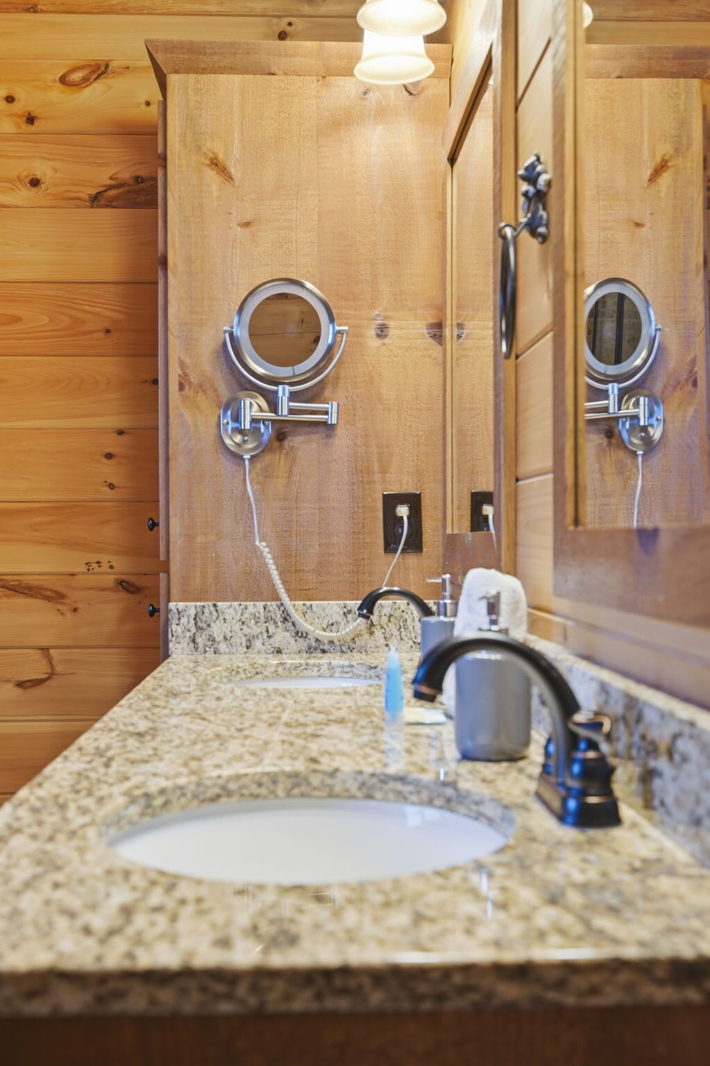 A bathroom with wooden paneling, a granite countertop, a sink, a mirror, and a towel rack.