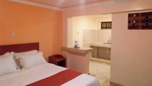 A hotel room with a bed, a desk, and a bathroom visible through an open door. - Camsupreme Studios Meru  (Meru)