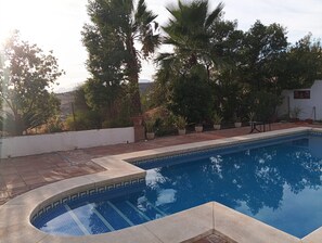 A swimming pool with a tiled edge, surrounded by potted plants and trees. - Villa La Malcontenta (Alcaucín)