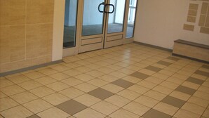 A hallway with a tiled floor, double doors with a handle, and a bench on the right. - 50 m from the sea, 3rd floor apartment with elevator, 60m2 all comforts (Saint-Jean-de-Monts)