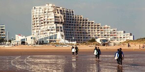 Un hotel frente a la playa con varios balcones y un diseño arquitectónico moderno.