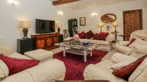 Ein Wohnzimmer mit Fernseher, Sofa, Sessel und Couchtisch.