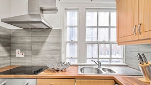 Una cucina moderna con piano cottura a gas, lavello in acciaio inox e mobili in legno.