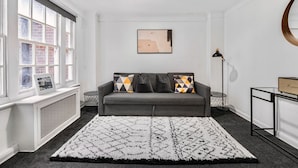 Un soggiorno moderno con un divano grigio, un tappeto decorato e un quadro appeso al muro.