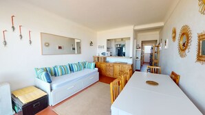 A compact living space with a sofa, dining table, kitchenette, and a large mirror. - Seafront apartment for 4 people (Canet-en-Roussillon)