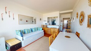 A compact living space with a sofa, dining table, kitchenette, and a large mirror. - Seafront apartment for 4 people (Canet-en-Roussillon)