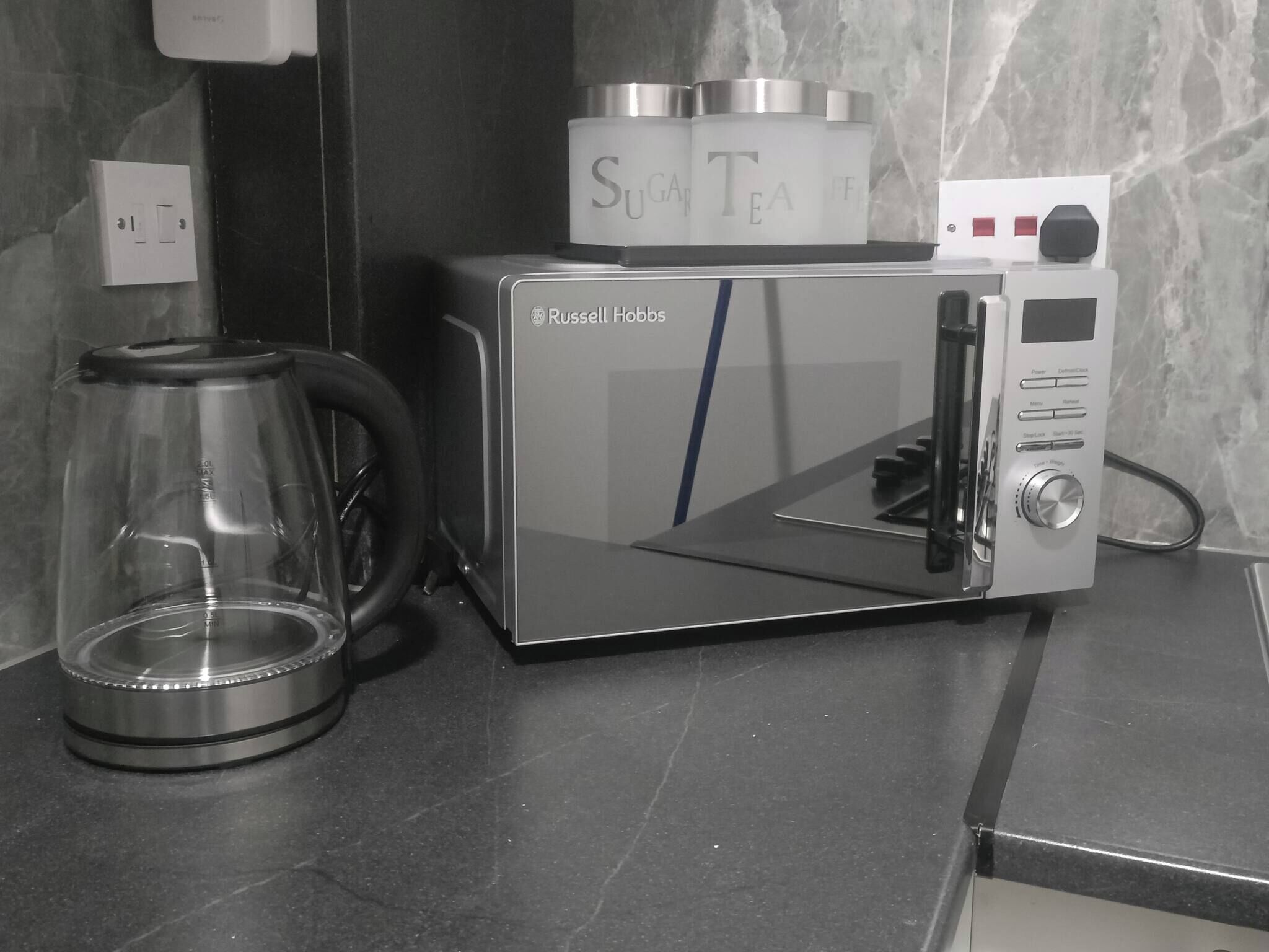 A compact, modern kitchen with a built-in coffee maker and a glass carafe.