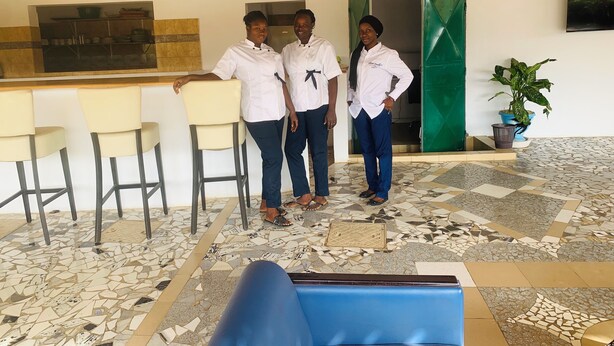 Una recepción con bar, tres personas con uniforme y un suelo estampado.