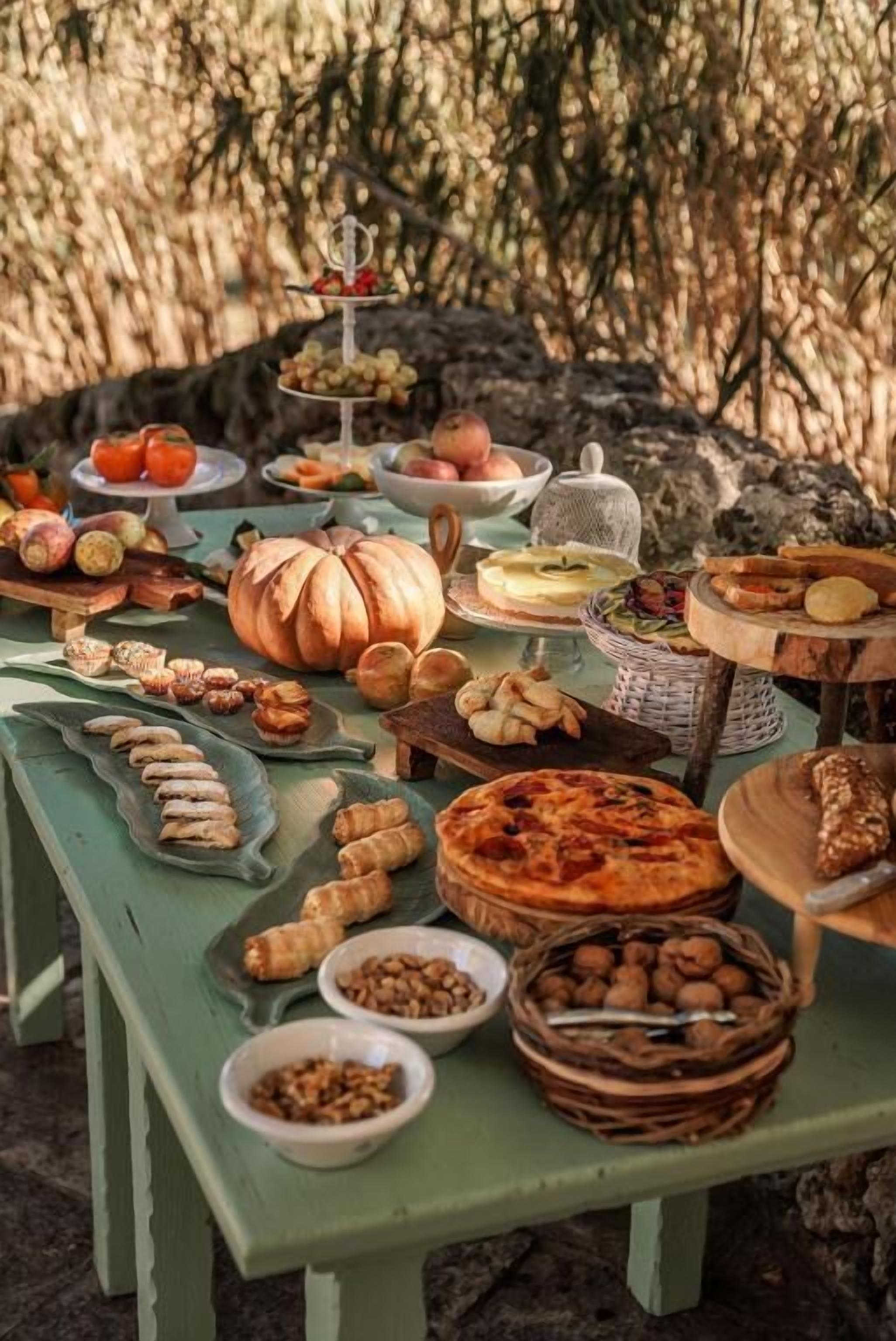 A picnic table with various food items and a pumpkin centerpiece.
