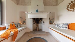 Un saló modern amb una llar de foc, dos sofàs amb coixins estampats, una catifa i una peça decorativa a la paret.