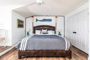 Une chambre à coucher avec un lit en bois, une tête de lit décorée d’un motif de poisson et un tableau encadré accroché au mur.