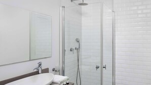 Ein modernes Badezimmer mit einem großen, weißen Waschbecken, einer Duschkabine aus Glas und einer Toilette.