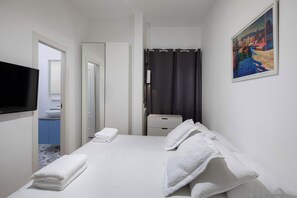 Una camera d'albergo con un letto, una televisione, un bagno e un quadro appeso al muro.