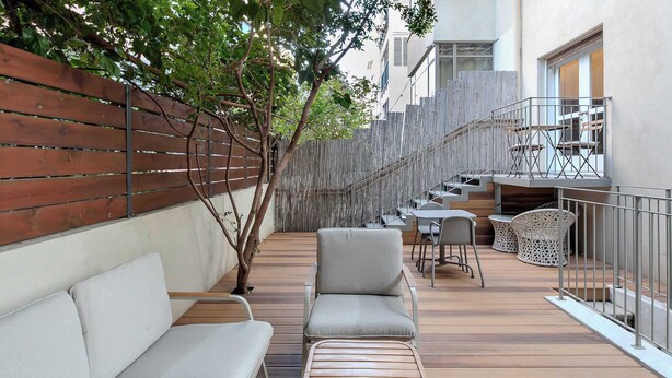 Eine Holzterrasse mit einer Sitzecke, einer Treppe und einem Balkon mit Stühlen.