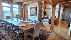 A spacious dining area with a wooden table and chairs, surrounded by large windows offering a view of the outdoors. - Huge Luxury Home, Hot Tub, Movie Theater, Mountain Views (Campton)