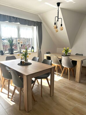 Un coin repas avec une table en bois, des chaises grises et une plante en pot.