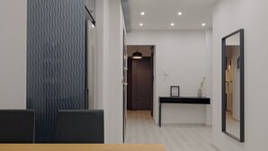 A modern hotel room with a wooden dining table, a dark-colored sofa, a patterned wall, a mirror, and a small plant on a console table. - Acropolis Deluxe Apartment, Apartment (Athens)