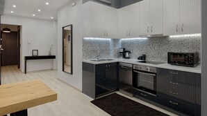 A modern kitchen with grey cabinets, a black countertop, and a tiled backsplash. - Acropolis Deluxe Apartment, Apartment (Athens)