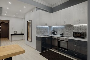 Eine moderne Küche mit grauen Schränken, einer schwarzen Arbeitsplatte und einer gefliesten Spritzschutzwand.