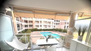Un balcon avec une table, des chaises et une vue sur une piscine et les bâtiments environnants.