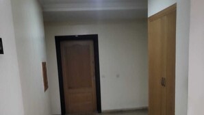 A hallway with a wooden door at the end, white walls, and a tiled floor. - Spacious  3-bedroom apartment in excellent Rabat Near Tram & City Center (Rabat)