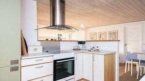 A compact kitchen with white cabinetry, a stainless steel range hood, and a built-in oven. - 6 Person Holiday Home in Juelsminde (Juelsminde)