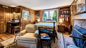Ein gemütliches Zimmer mit Bett, Stuhl, Schreibtisch, Bücherregal und Kamin.