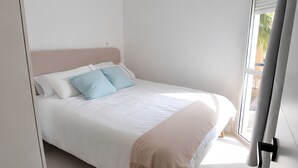 Een slaapkamer met een bed, een raam en een deur.