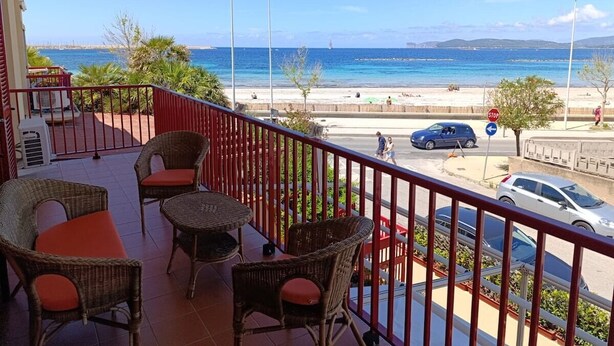 Un balcone con mobili in vimini e vista sulla spiaggia e sul mare.