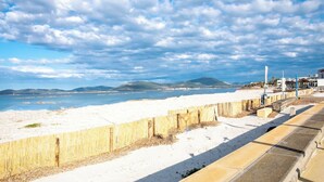 Una spiaggia con una recinzione di legno e un vialetto in cemento.