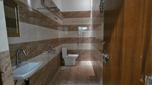 A modern bathroom with a sink, toilet, and bidet. The walls are tiled with a striped pattern. - Relax With Ramayana (Ayodhya)