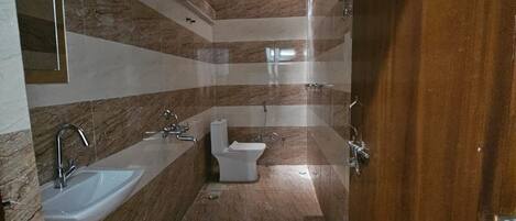 Un baño moderno con lavamanos, inodoro y bidé. Las paredes están cubiertas de azulejos con un estampado a rayas.