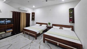 A hotel room with two wooden beds, a ceiling fan, a TV, a plant shelf, and a marble floor. - Relax With Ramayana (Ayodhya)
