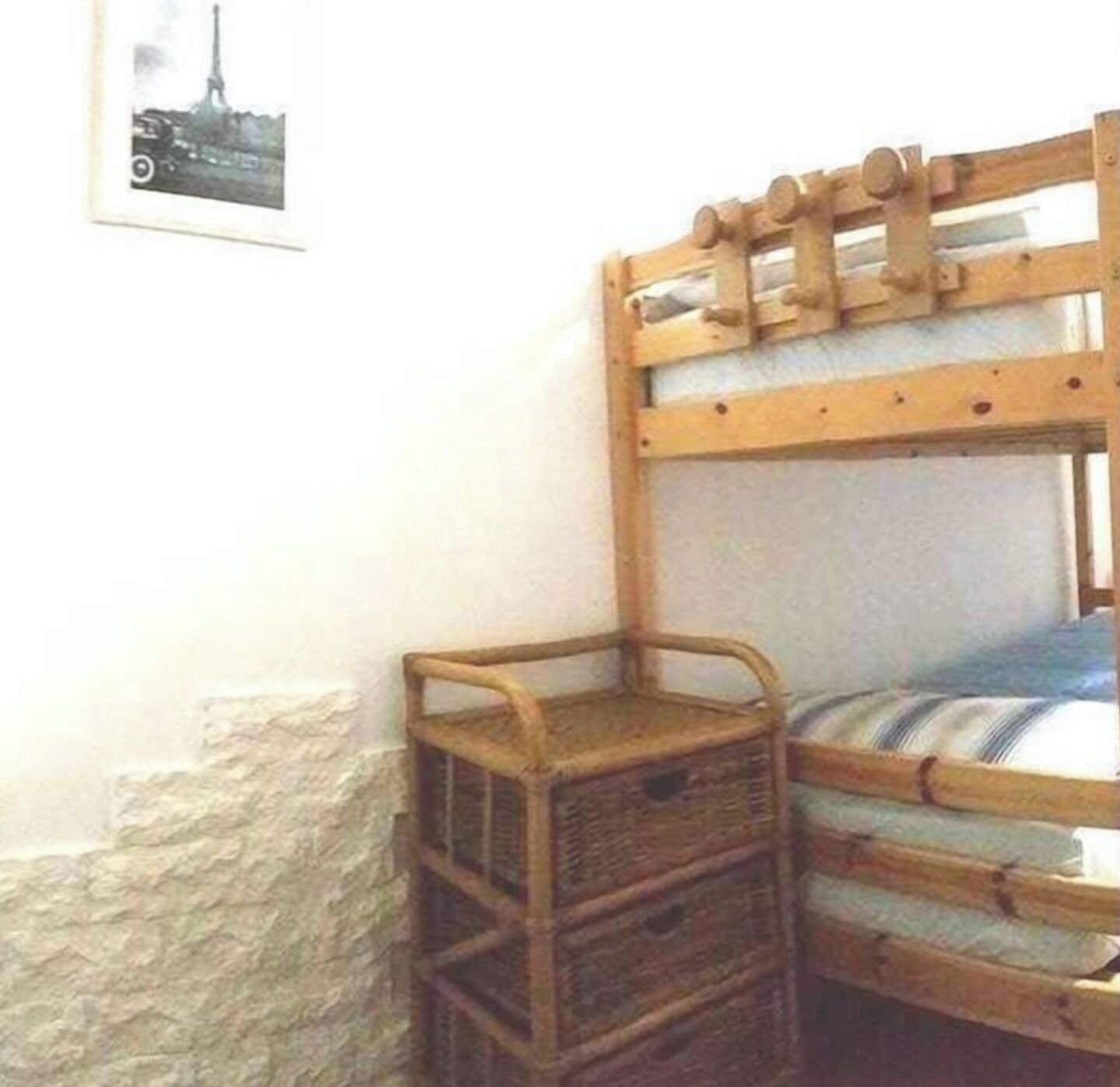 A bunk bed with a wooden headboard and a small wooden chest beside it.