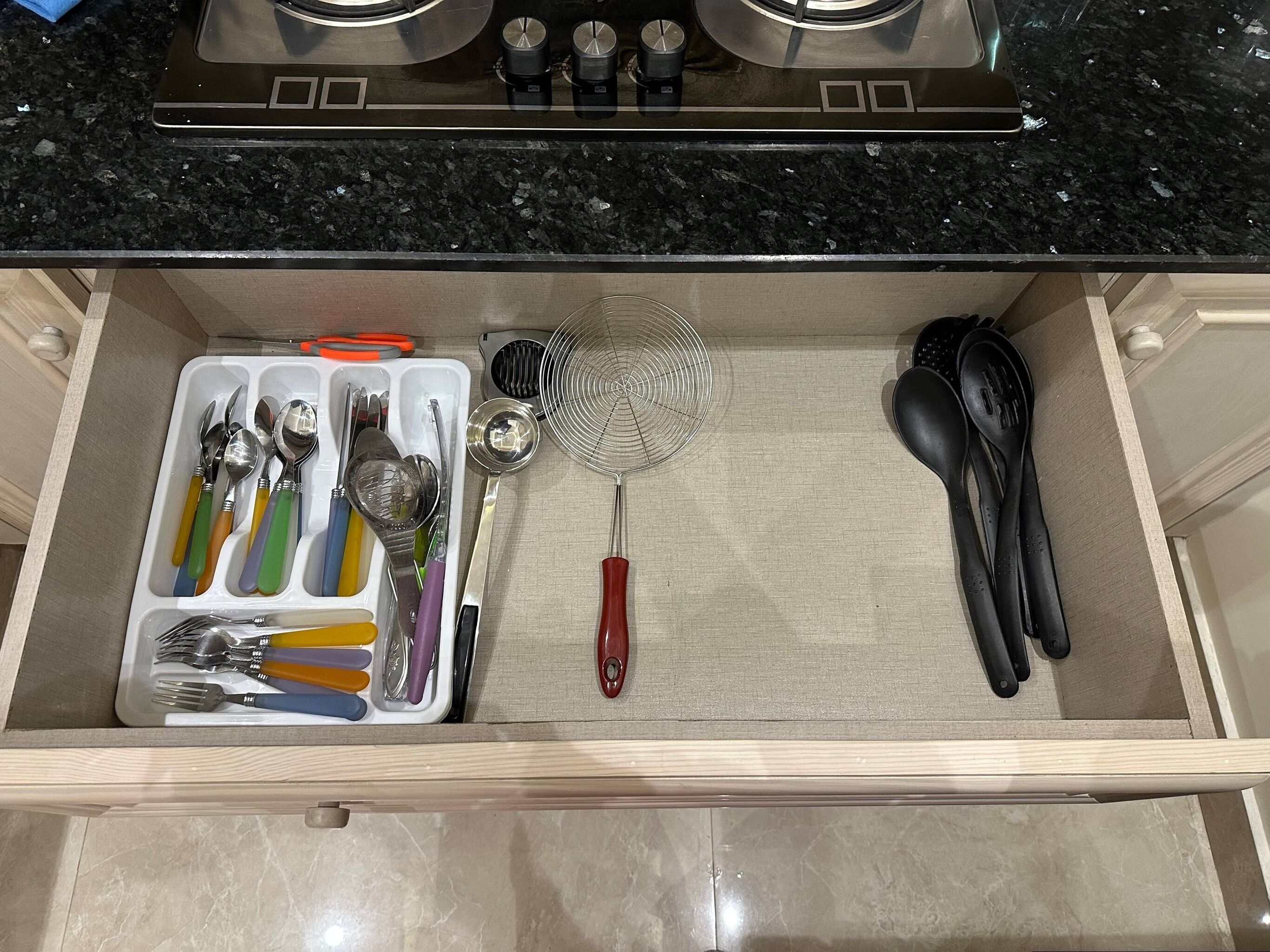 A kitchen drawer with utensils, a whisk, and a spatula.