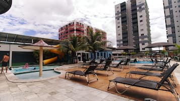 Een buitenzwembad, parasols bij het zwembad en ligstoelen