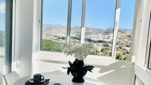 A round table with a vase of white flowers, two matching cups, and a woven placemat. - Mirador del Faro Apartment Torrox Costa (Torrox Costa)