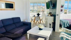 A modern living room with a sofa, coffee table, and dining area. - Mirador del Faro Apartment Torrox Costa (Torrox Costa)