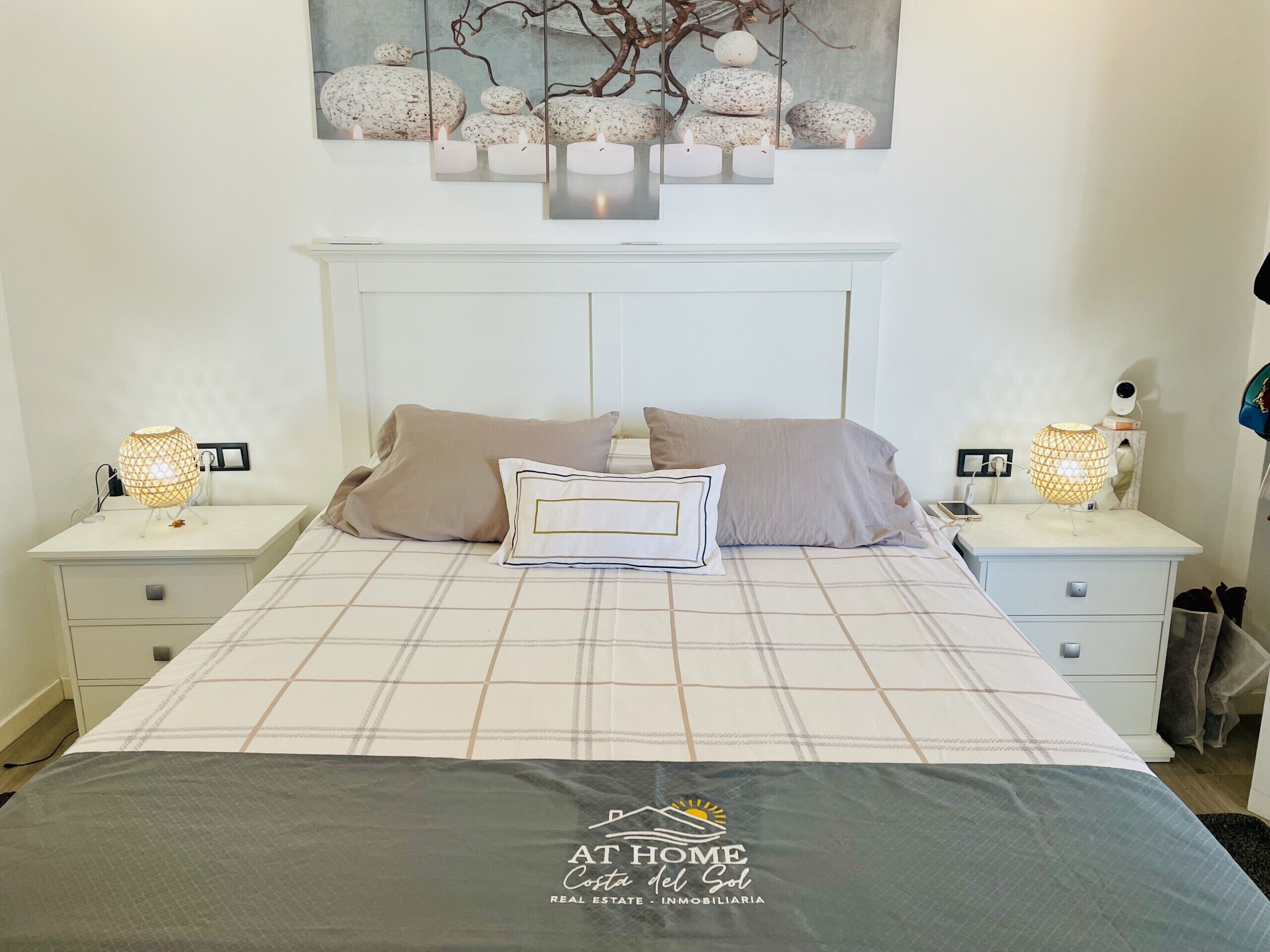A neatly arranged bedroom with a bed, two bedside tables, and a wall-mounted light fixture.