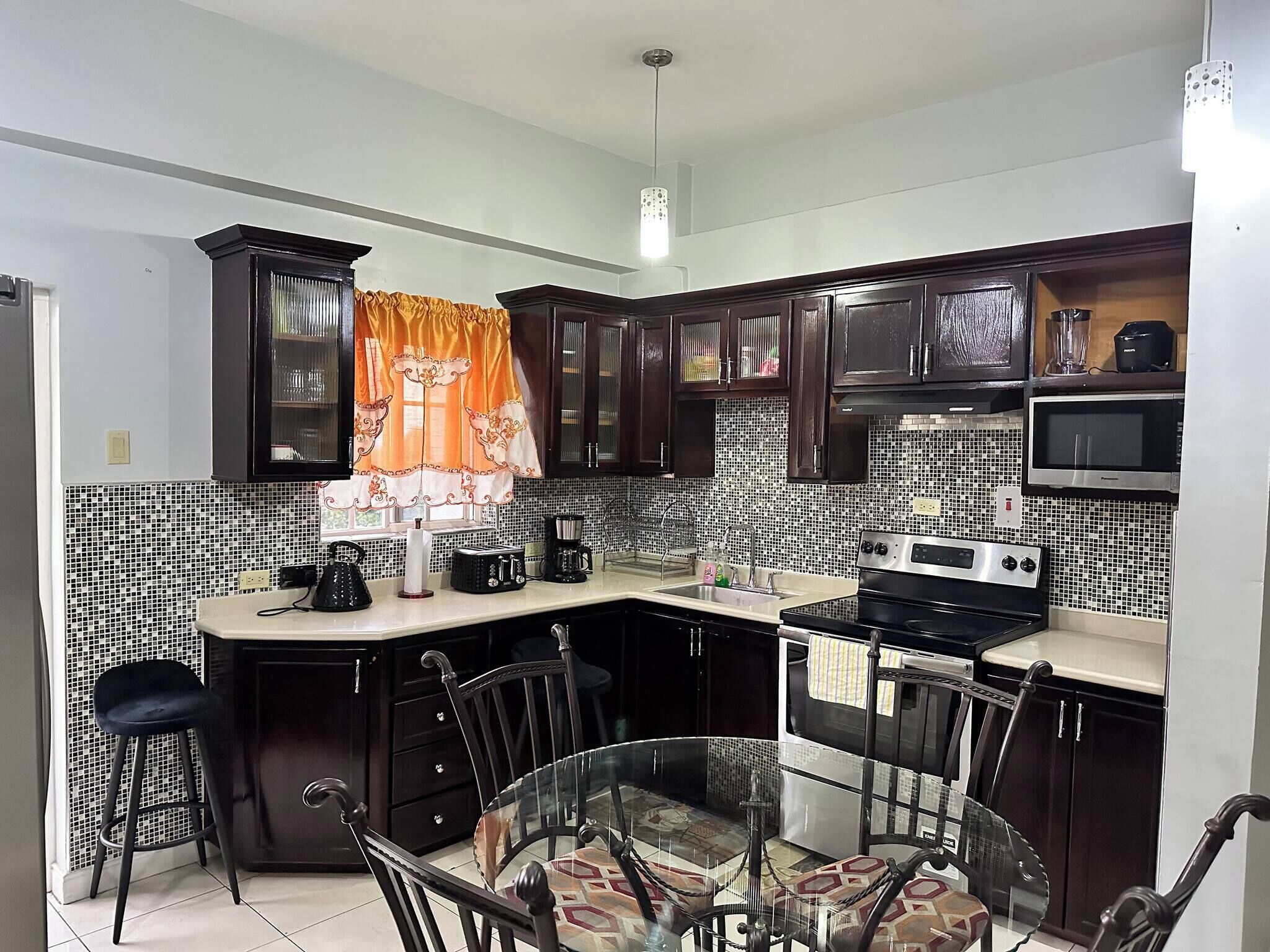 A kitchen with dark wooden cabinets, a microwave, a stove, and a sink.