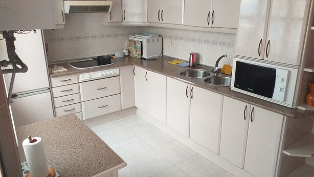 A kitchen with white cabinets, a stove, a microwave, and a sink. - Exterior Double Room Toledo (Toledo)
