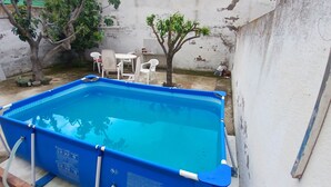 A rectangular swimming pool with a blue interior, surrounded by a white wall. There are white plastic chairs and a small tree in the background. - Exterior Double Room Toledo (Toledo)