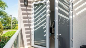 Varanda moderna ao ar livre com porta de vidro que dá para o interior, pérgola e vista para o verde.