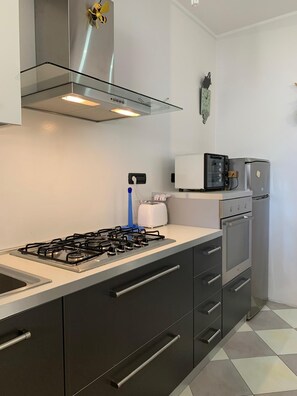 A modern kitchen with a gas stove, stainless steel appliances, and a built-in oven. - A Glimpse of the Sea (Alghero)