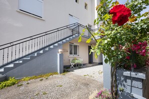 A staircase leading to a building with a small table and chairs outside, surrounded by gravel and plants. - Le Cyclamens – Comfortable Stay Near Rodez, Ideal for 2 Guests (Onet le Château)